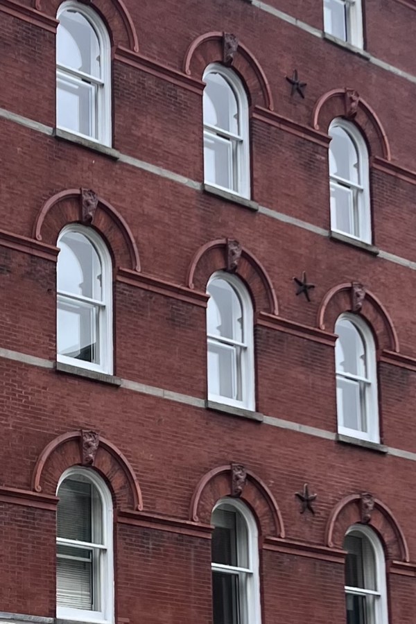 Red brick building with rows of arched white windows and small star ornaments
