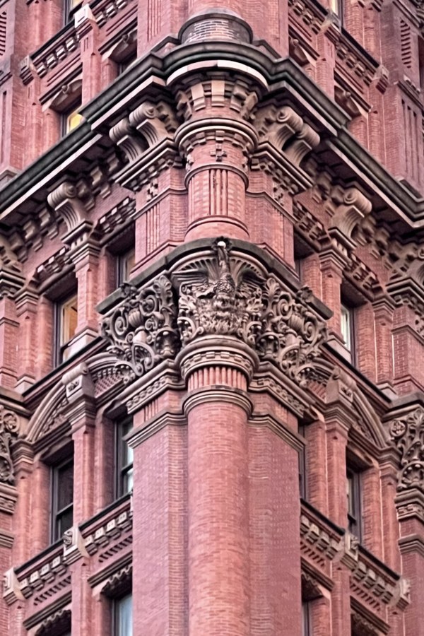 Red brick corner tower with ornate carved column capitals