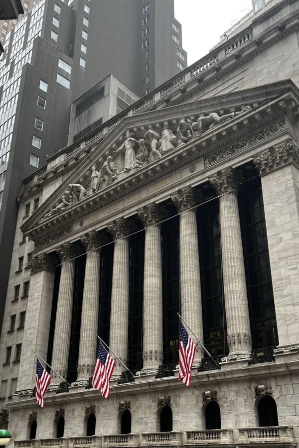 Classical stone building with tall columns, a sculpted pediment, and two American flags